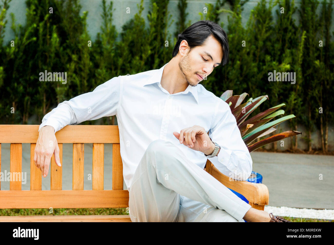 Businessman sitting on bench checking the time Stock Photo - Alamy