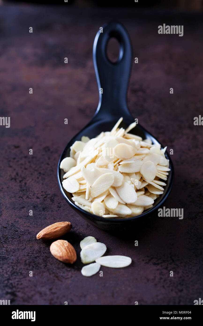 Spoon of sliced and blanched almonds on rusty ground Stock Photo