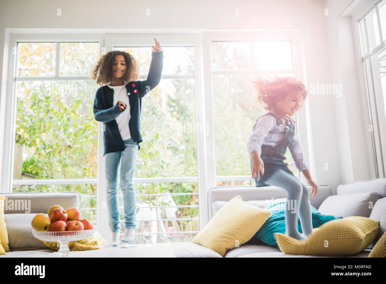 Happy girls jumping and hopping on couch Stock Photo Alamy
