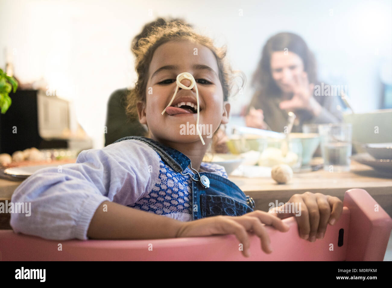 Portrait of a cheeky little girl eating spaghetti Stock Photo