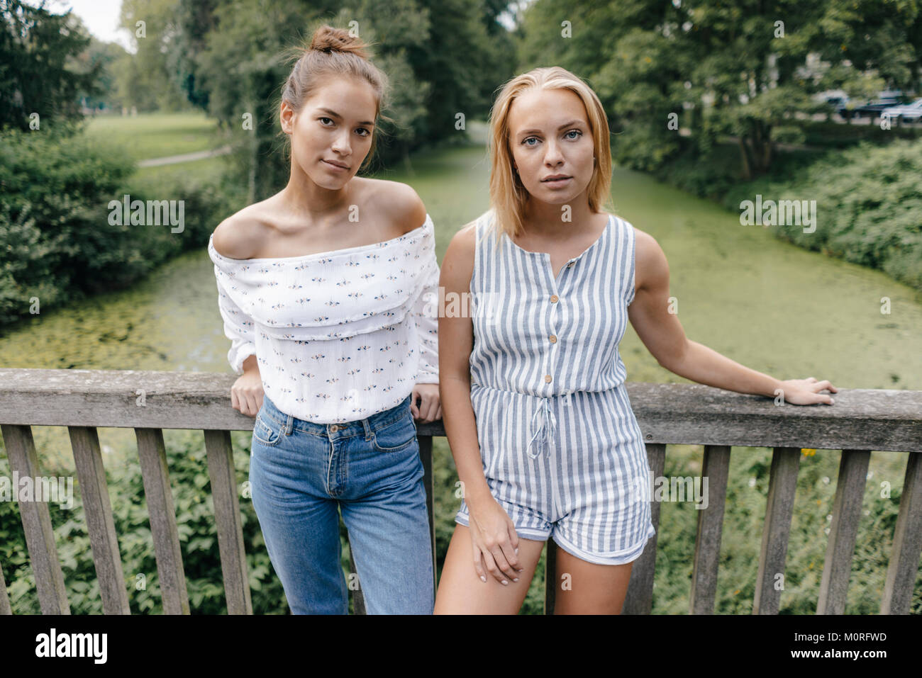 Portrait of two young women standing on a bridge Stock Photo - Alamy