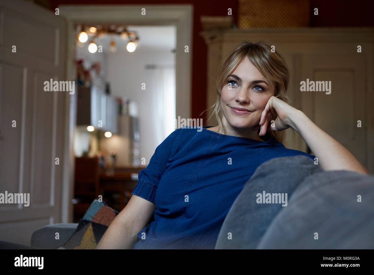 Portrait of smiling woman relaxing on couch at home Stock Photo - Alamy