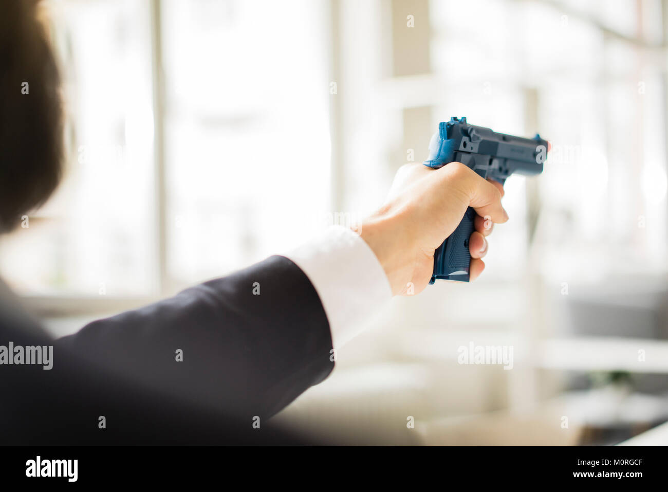 Businessman aiming with gun in office Stock Photo