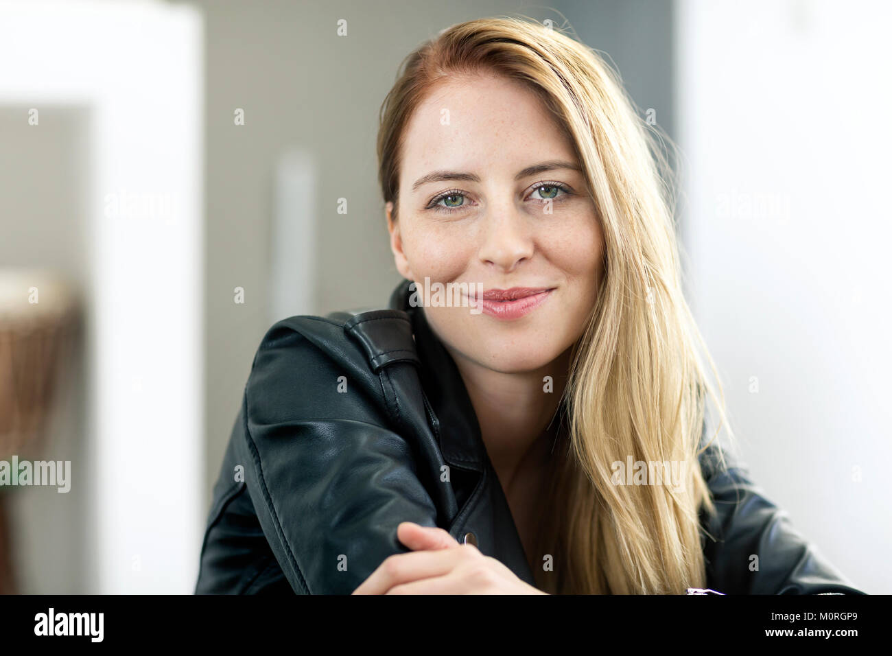 Portrait of smiling young woman wearing leather jacket Stock Photo - Alamy