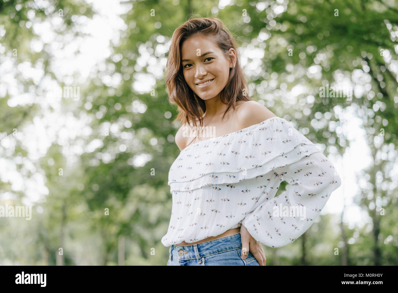 Portrait of smiling young woman in a park Stock Photo - Alamy