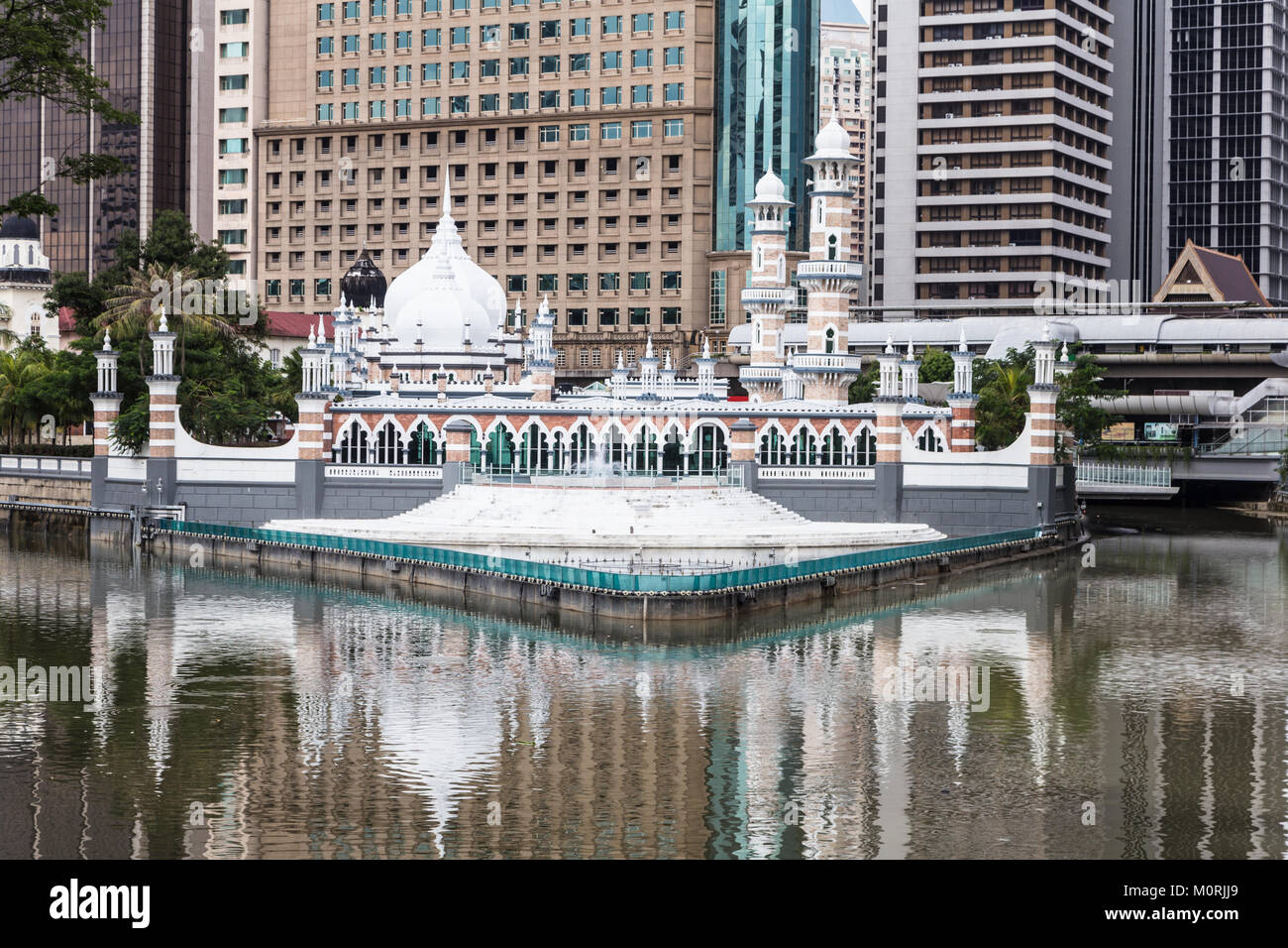 The office buildings reflects in the water of the Klang river, where it meets the Gombak river, in front of the Jamek mosque (masjid) in the heart of  Stock Photo