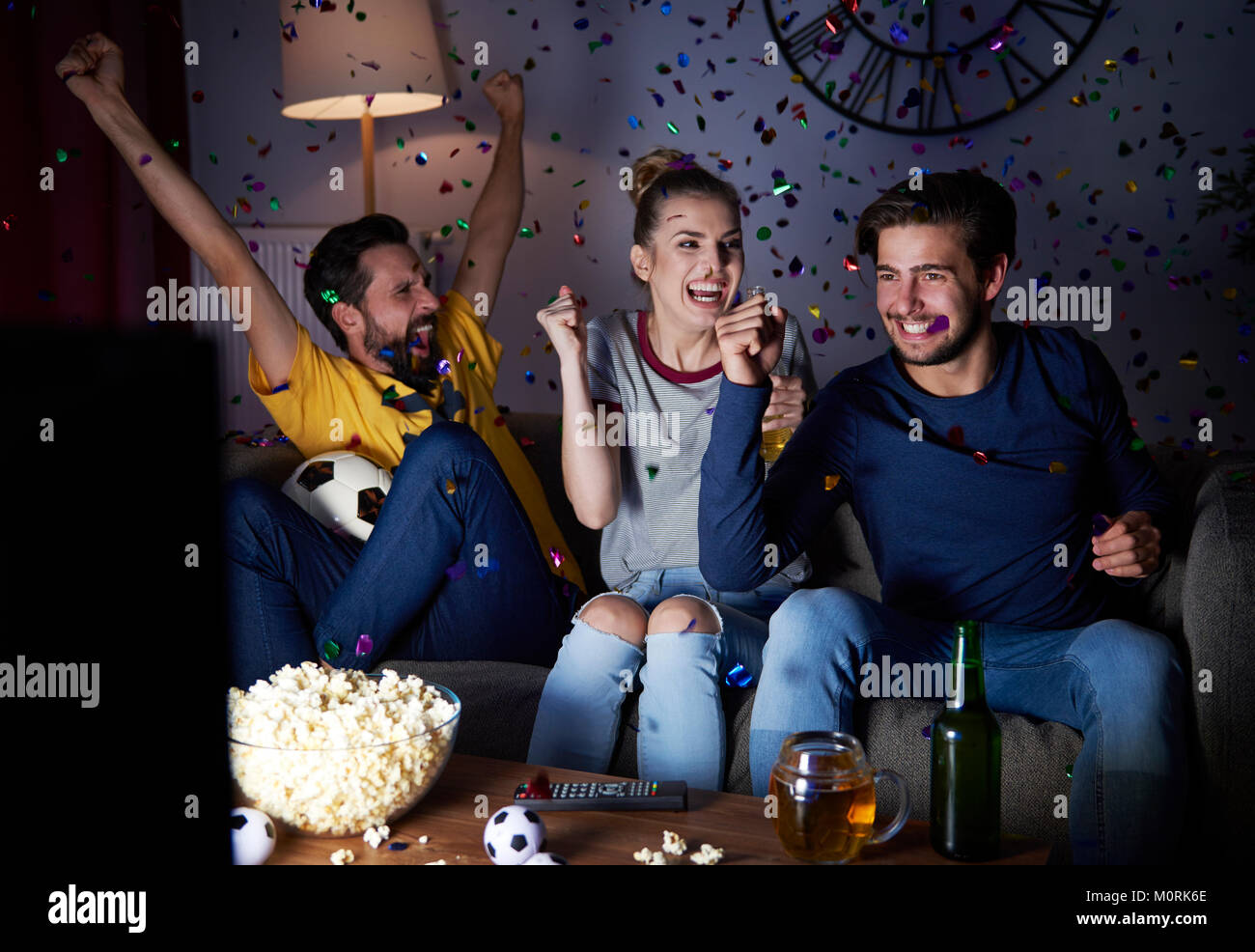 Excited friends sitting on the sofa watching Tv Stock Photo