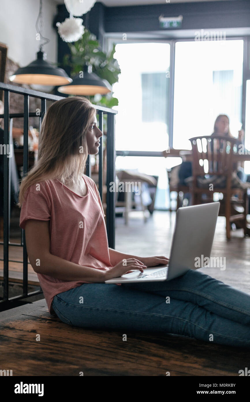 Young woman sitting in cafe, using laptop Stock Photo - Alamy
