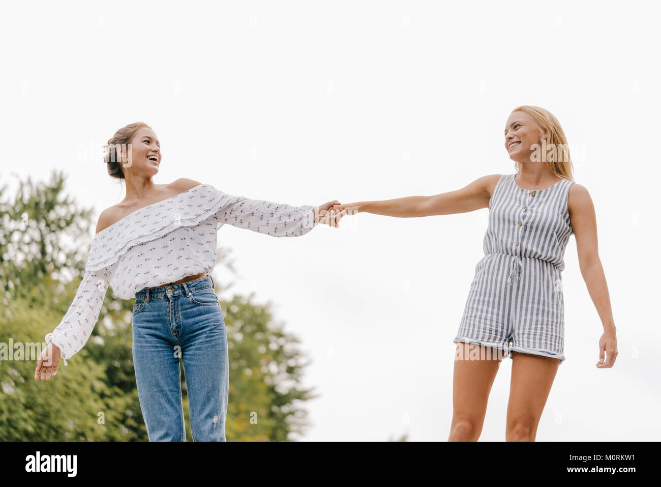 Two happy young women holding hands outdoors Stock Photo - Alamy