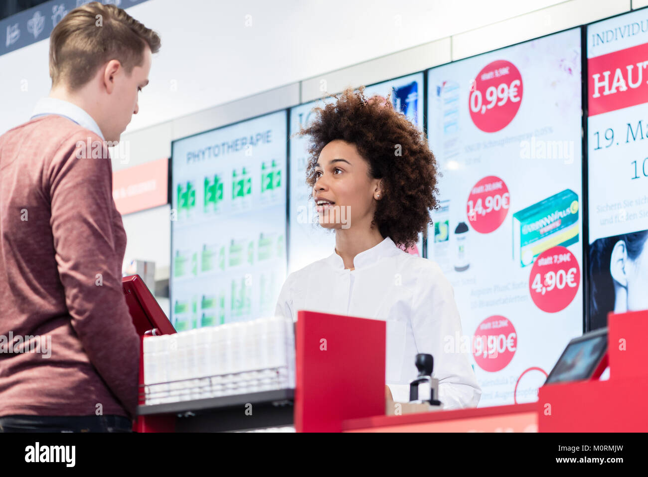 pharmacist answering question of a young customer in a modern dr Stock Photo