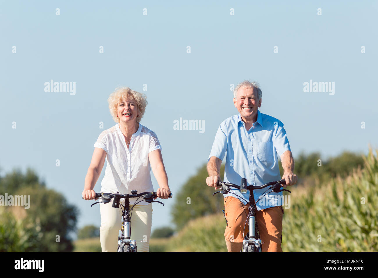 Senior couple looking forward with confidence while riding bicyc Stock Photo