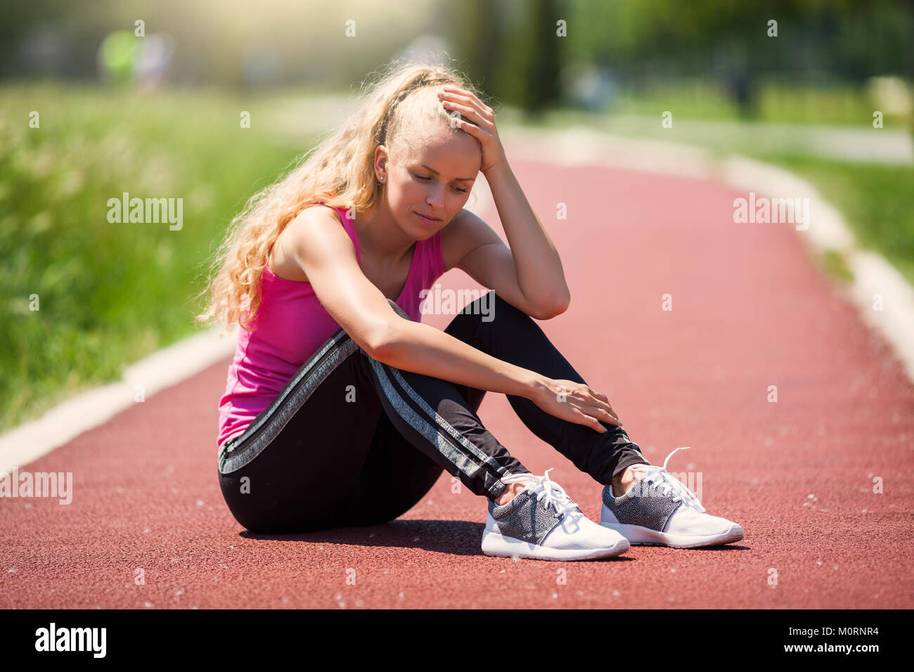 Young woman is sad because she got injured while jogging. Stock Photo