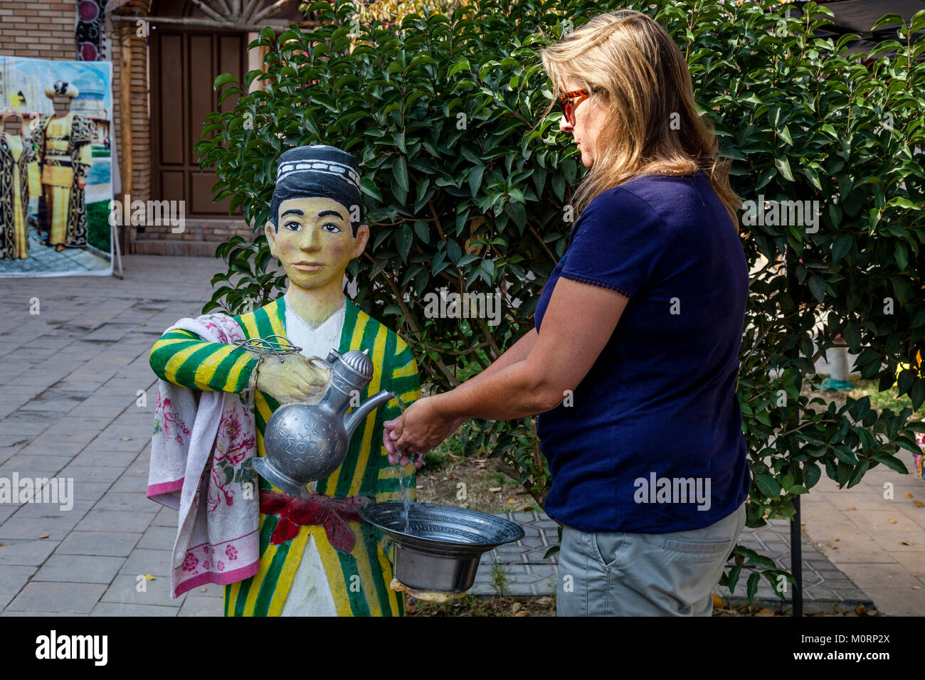 A Female Tourist Washes Her Hands At A Traditional Fountain In The Courtyard Of A Cafe, Samarkand, Uzbekistan Stock Photo