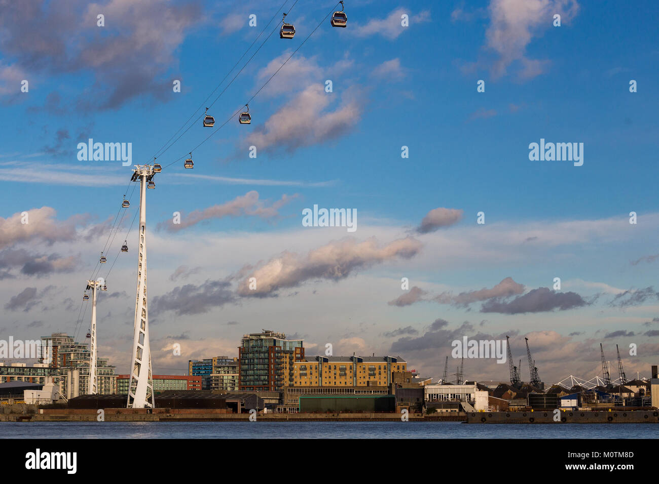 Emirates Air Line Cable Cars crossing the Thames with starting plane in the background, North Greenwich, London, January 2018 Stock Photo