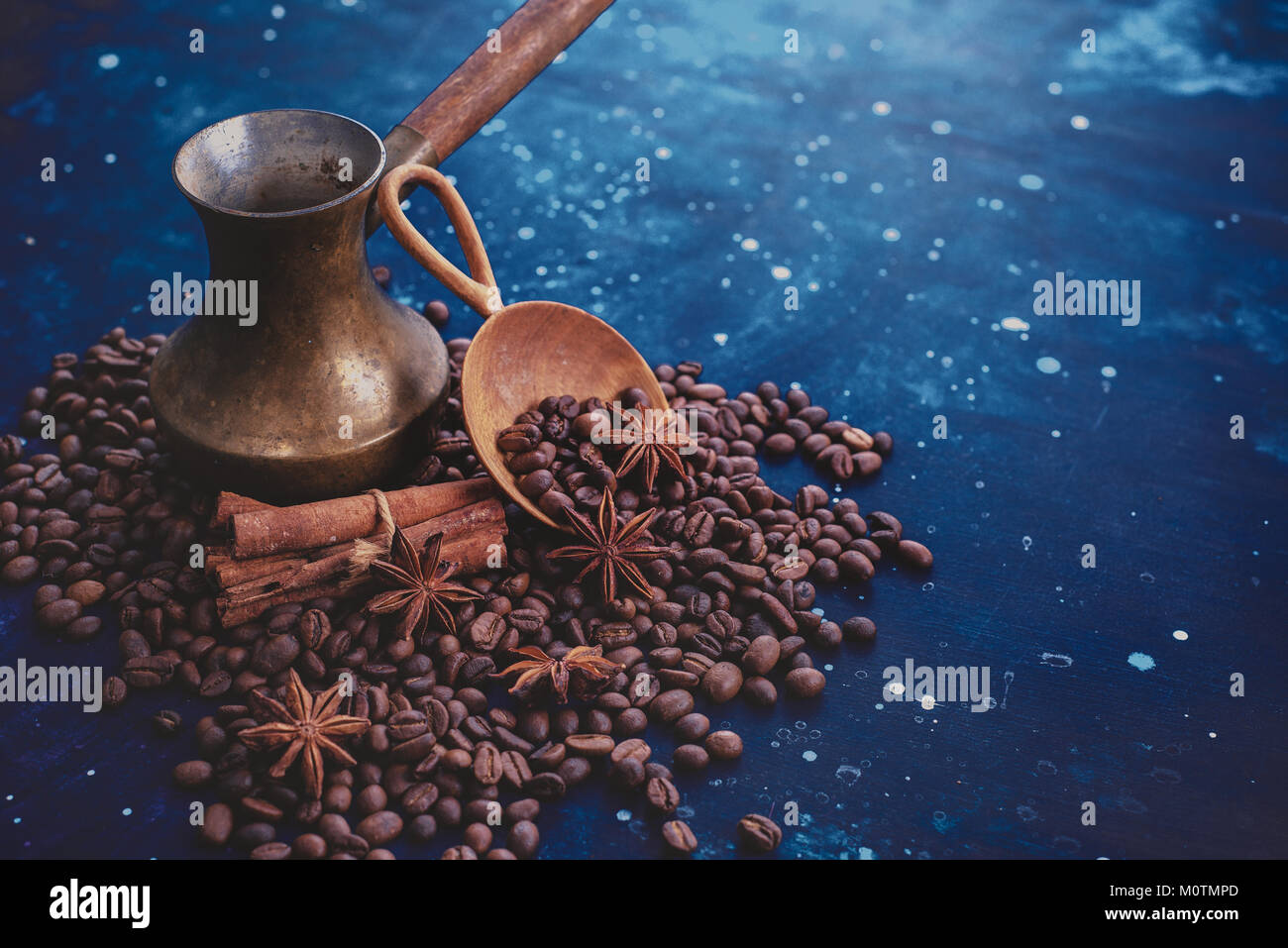 ?opper cezve on scattered coffee beans with handmaiden wooden scoop, cinnamon and anise stars on a dark background. Header or title image with copy sp Stock Photo