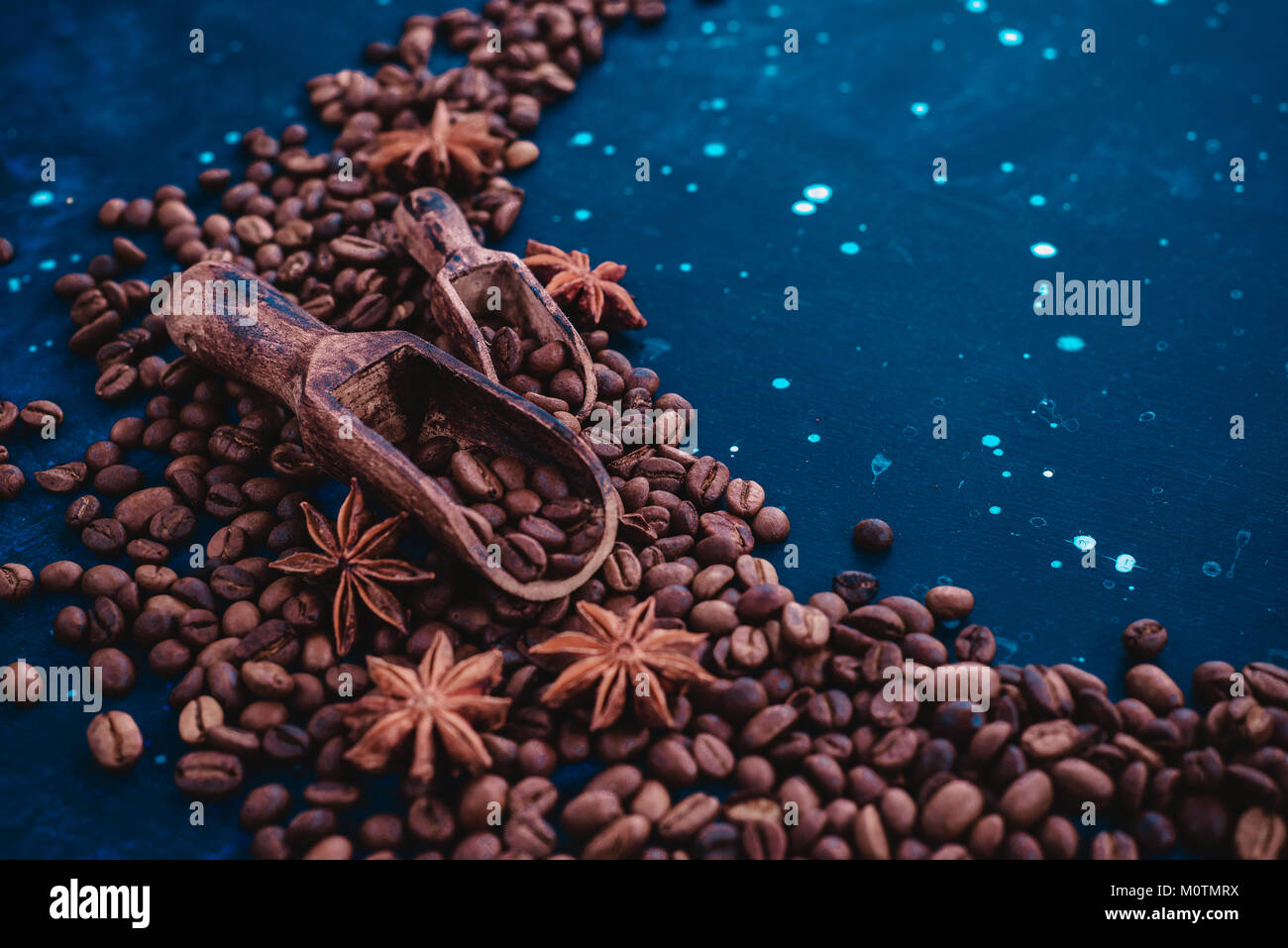 Close-up of two wooden scoops for coffee beans with cinnamon and anise stars on a dark blue background. Vintage barista concept. Stock Photo