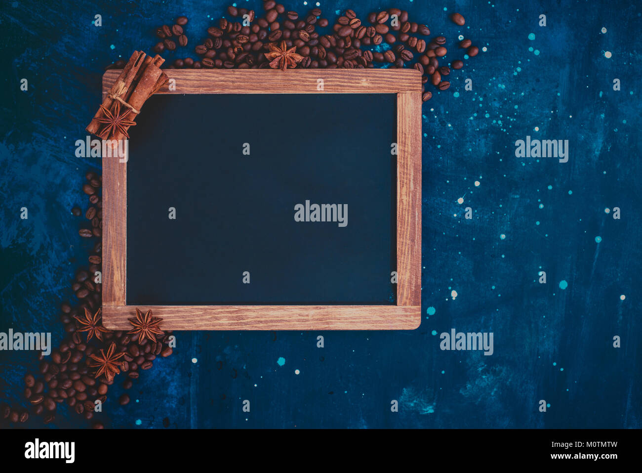 Blackboard frame with coffee beans, cinnamon and anise stars on a dark blue background. Header or title image with copy space. Top view dark food phot Stock Photo