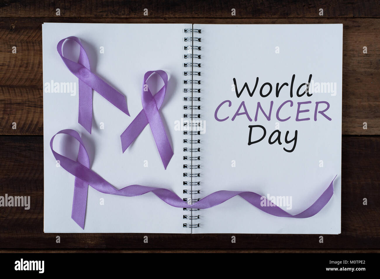 book with WORLD CANCER DAY text and lavender ribbon. symbol of all cancer concept Stock Photo