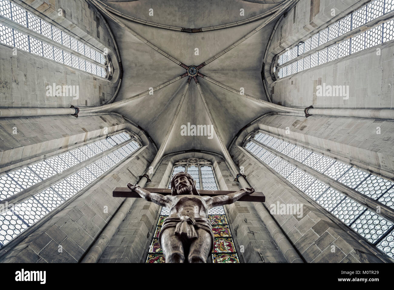 Bottom to top perspective of an franciscan church dome in Esslingen,Germany. The foreground shows a jesus with cross. Stock Photo