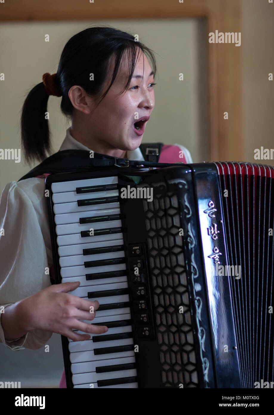 North Korean waitress in a restaurant singing and playing accordion