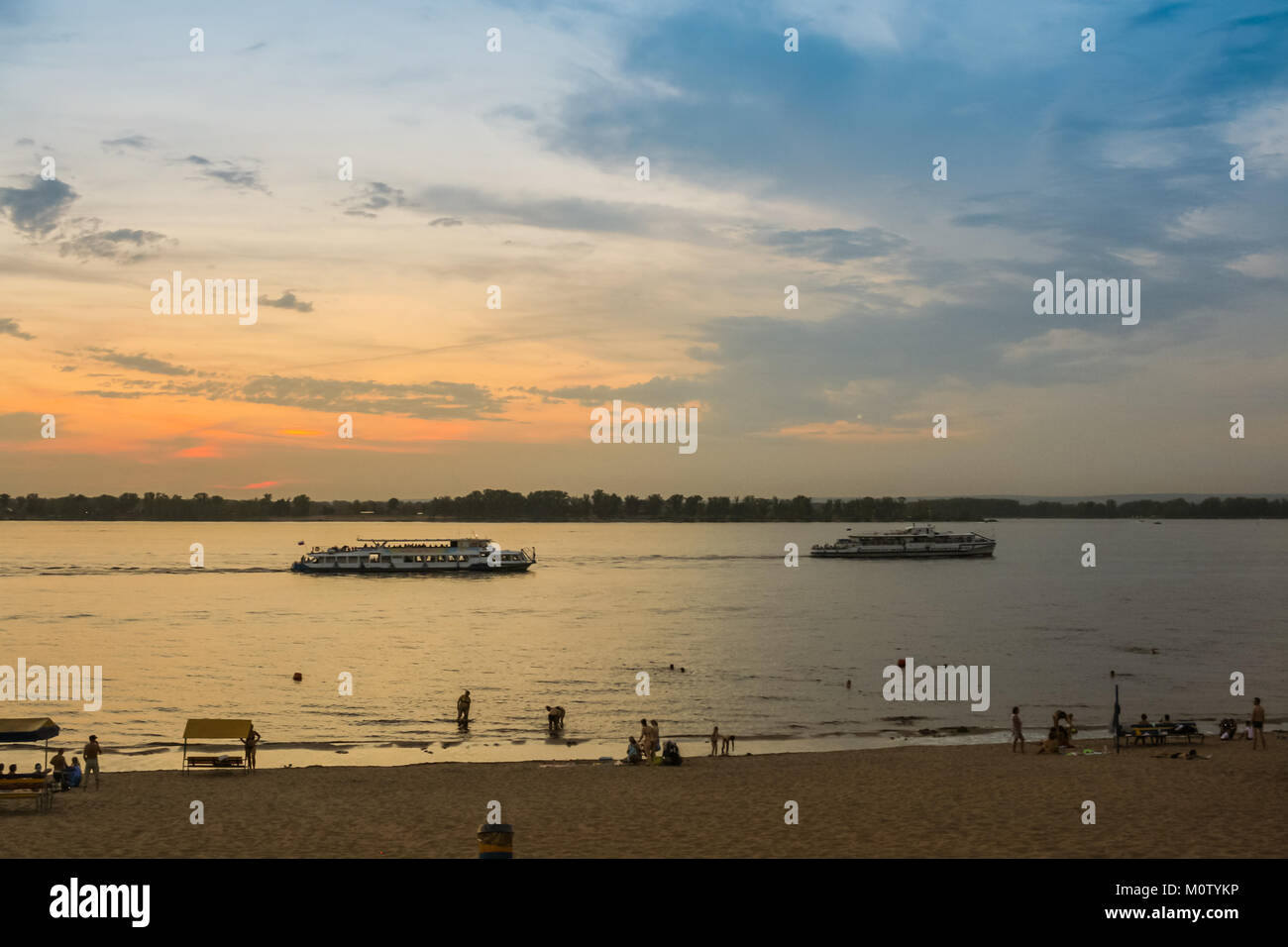 Sunset on the Volga river with pleasure boats and bathing people. Stock Photo