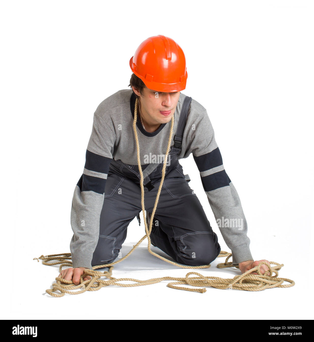 A young worker in grey uniform tied up with rope on white isolated background. Stock Photo