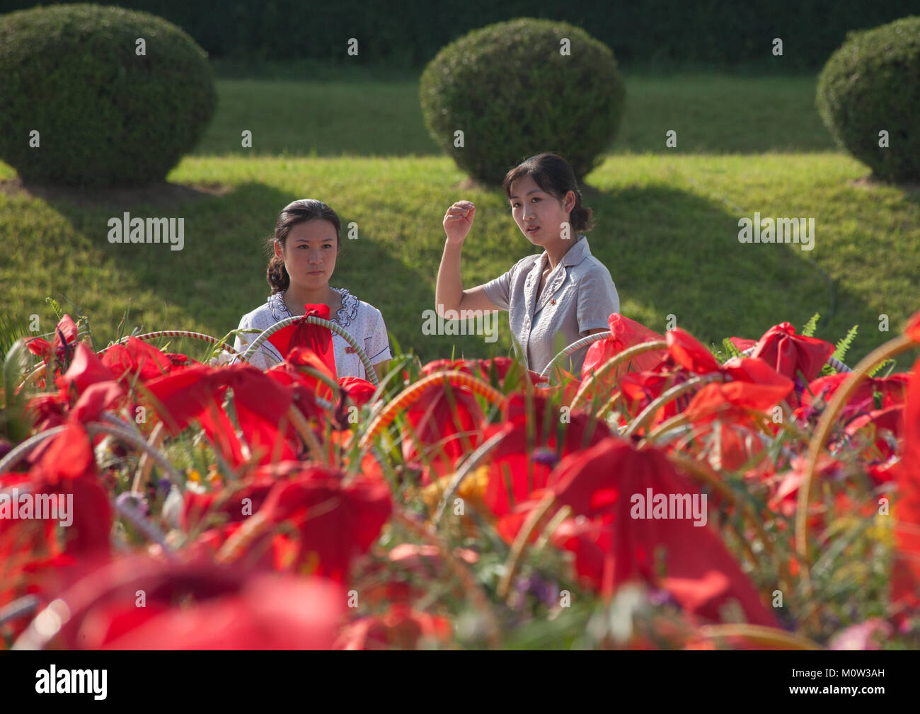 North Korean women in front of bunches of flowers in Mansudae Grand monument, Pyongan Province, Pyongyang, North Korea Stock Photo