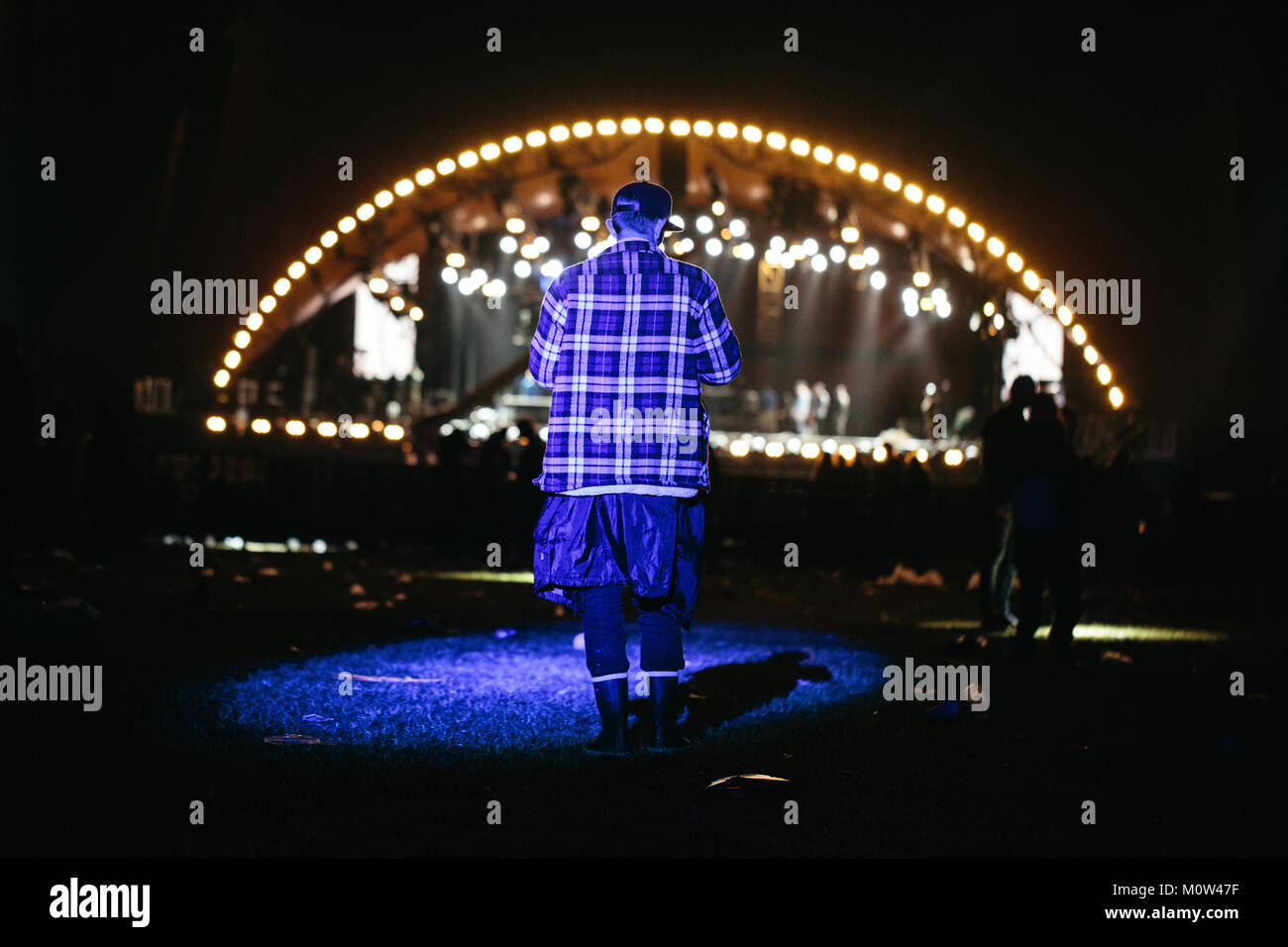 A lonely festivalgoer stands in the limelight in front of Orange Stage at the Danish music festival Roskilde Festival 2016. Denmark, 01/07 2016. Stock Photo