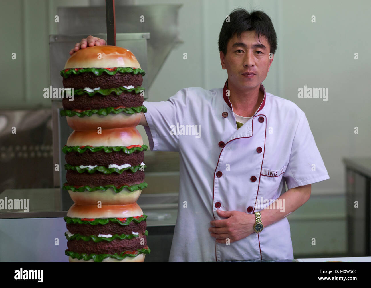 North Korean cook with a giant hamburger in a fast food restaurant