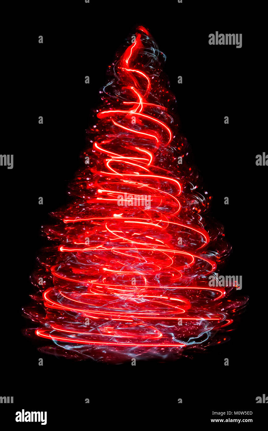 A small spinning artifical Christmas tree producing a cone-shaped corkscrew of blurred red light. Stock Photo