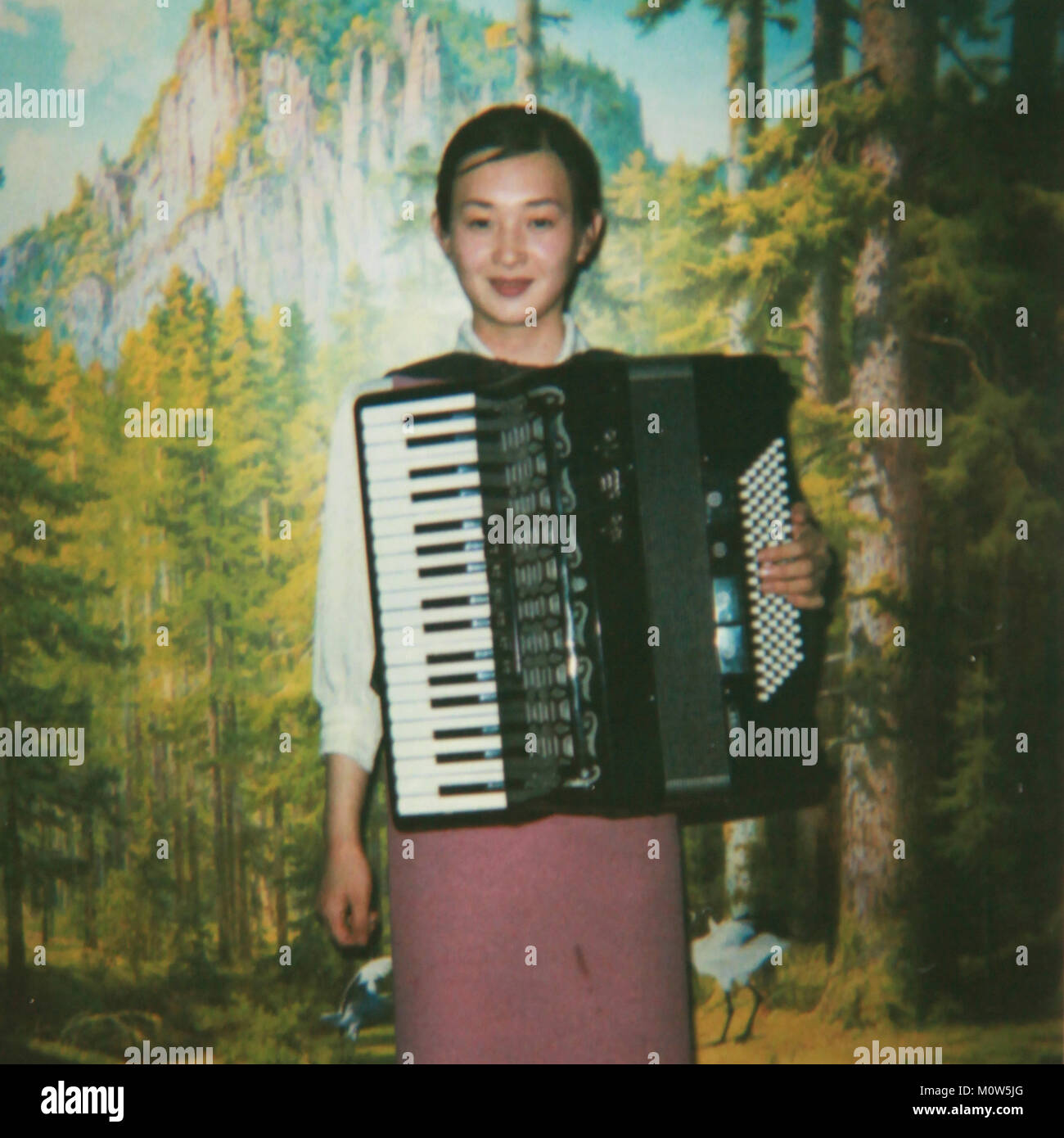 Polaroid of a smiling North Korean waitress playing accordion, Pyongan