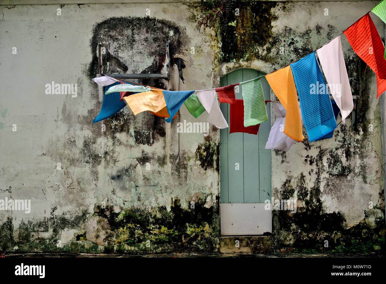 Traditional Buddhist prayer flags hanging on a clothes line on the weathered of a shop house in Geylang Singapore Stock Photo