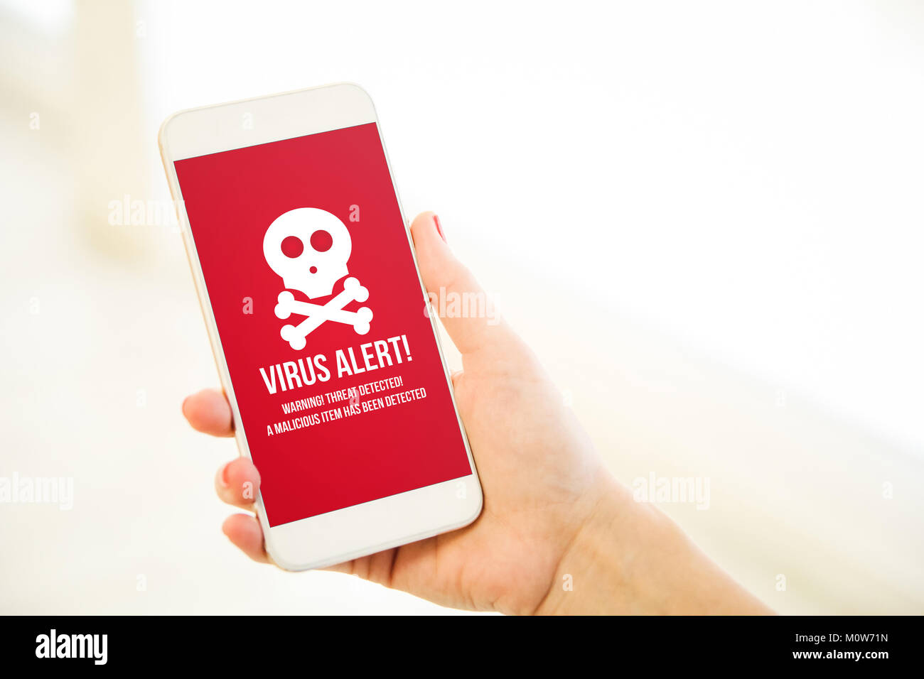 Woman holding a pink gold generic smartphone showing virus alert Stock Photo