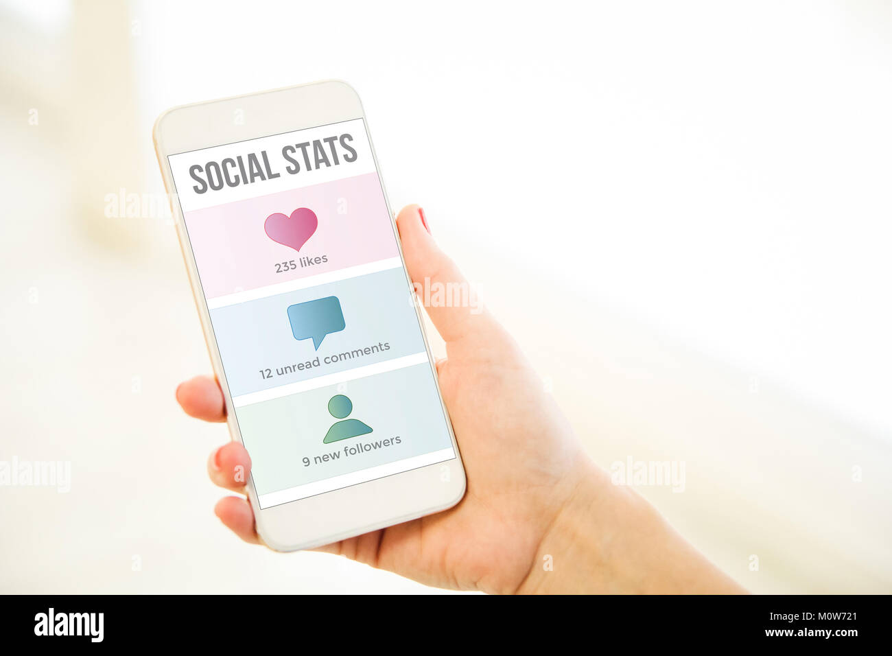 Woman holding a pink gold generic smartphone showing social stats Stock Photo