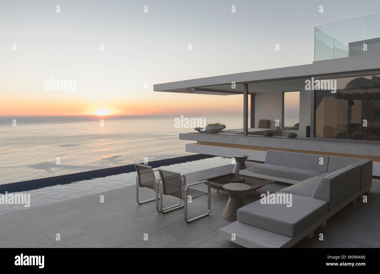 View of sunset over ocean horizon from modern, luxury home showcase exterior patio Stock Photo