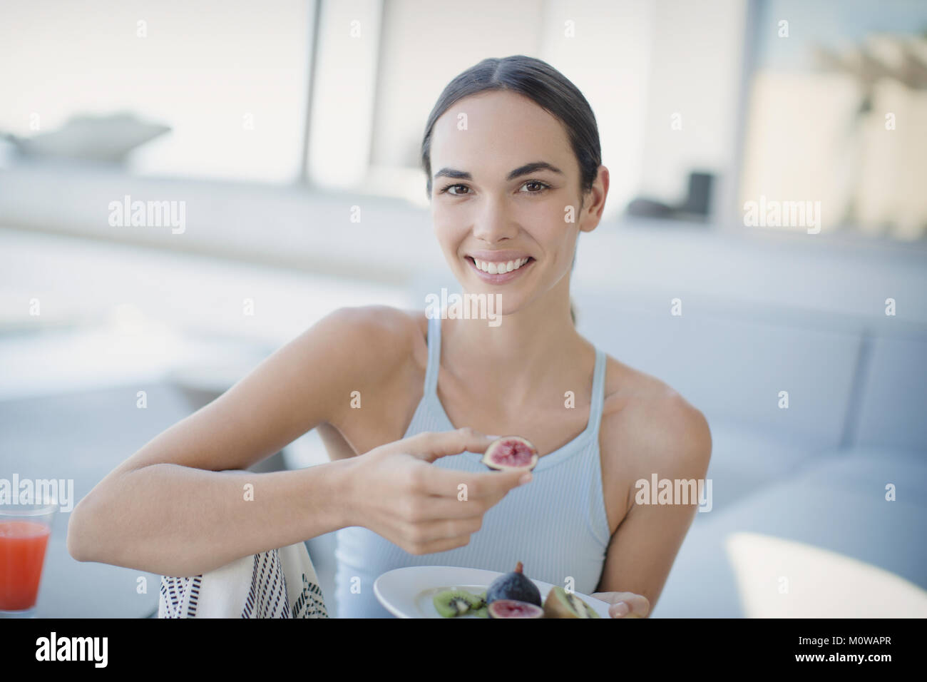 Portrait smiling, confident brunette woman eating figs Stock Photo