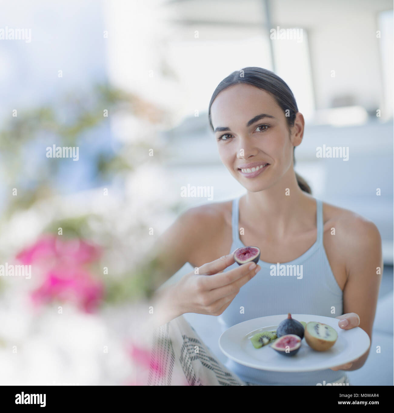 Portrait smiling brunette woman eating figs and kiwi Stock Photo