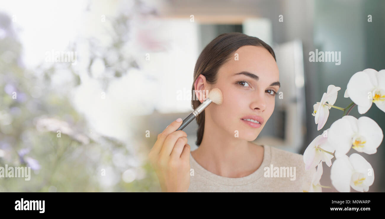 Brunette woman applying makeup with powder brush Stock Photo