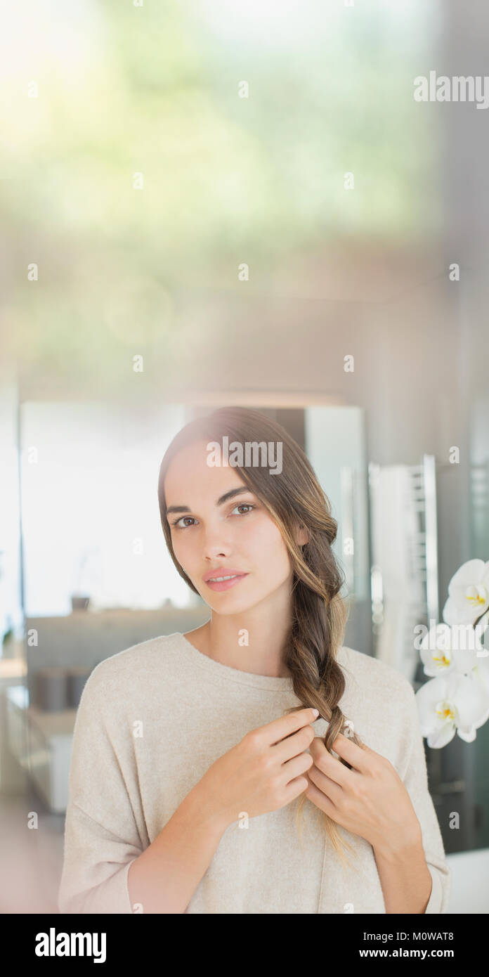 Portrait serious brunette woman braiding hair Stock Photo