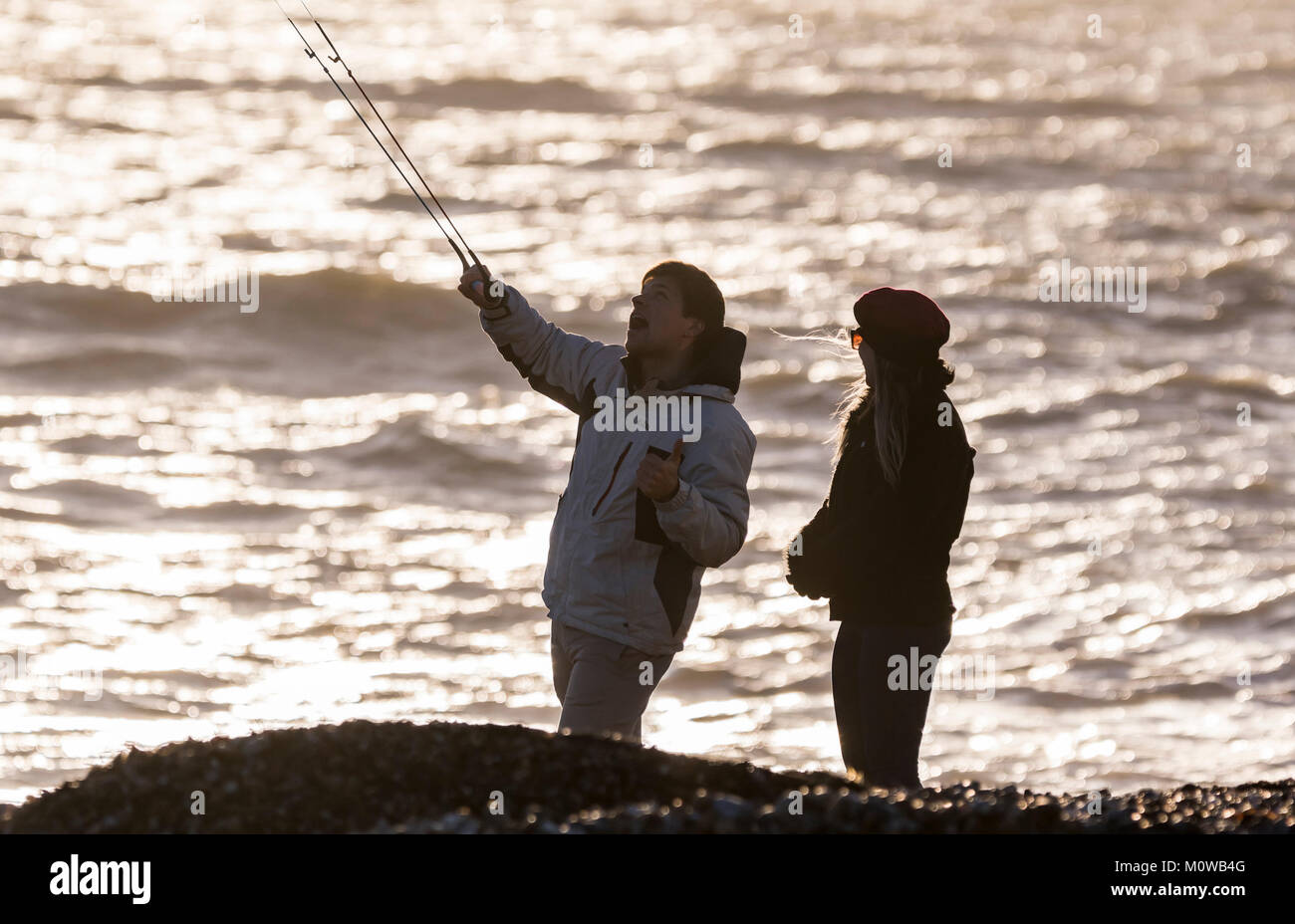 Couple on a beach flying a kite in late evening light Stock Photo - Alamy