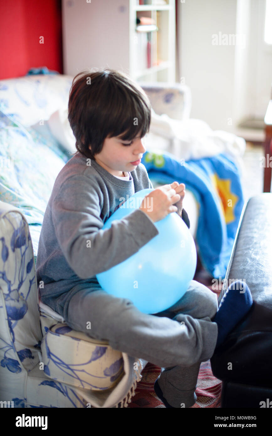 Child With Inflated Blue Balloon For Party Sitting On Sofa Child With Inflated Blue Balloon For Party Sitting On Sofa