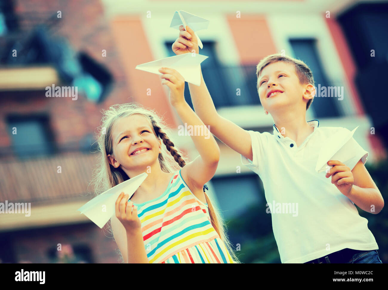 Two smiling kids playing with flying paper planes outdoors Stock Photo ...
