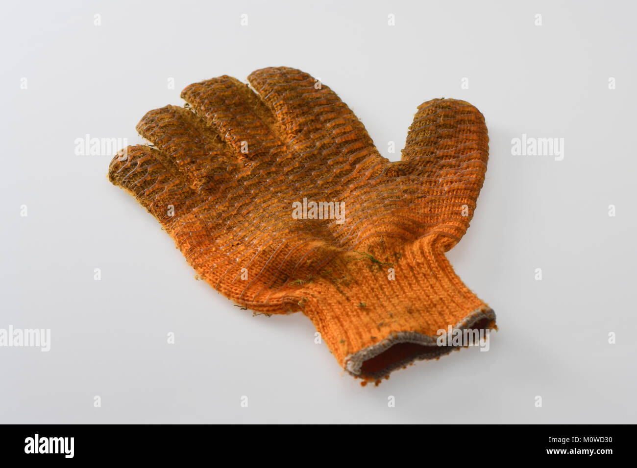A right hand orange dirty gardening glove laid  flat on white background Stock Photo