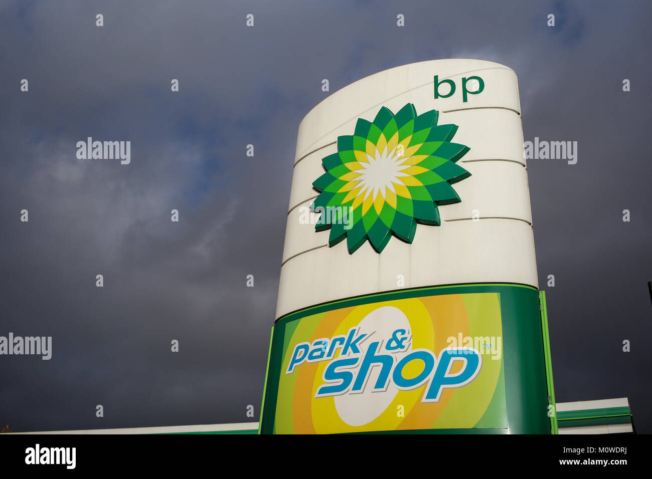 BP petrol garage sign with park and shop logo against a stormy sky. Stock Photo