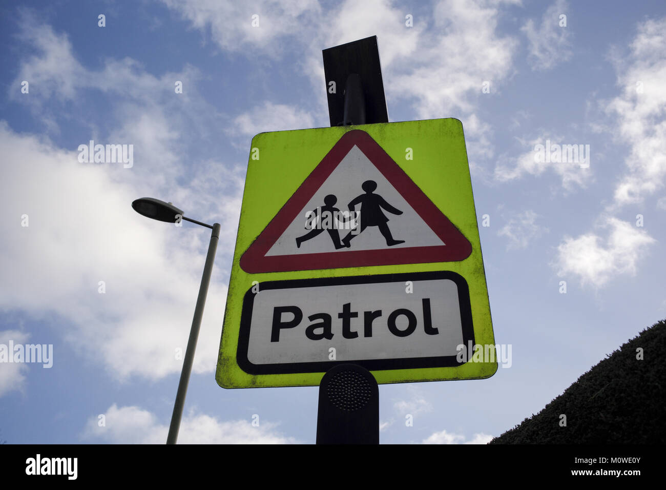 School crossing patrol sign in luminous green with a sky background viewed from below. Stock Photo