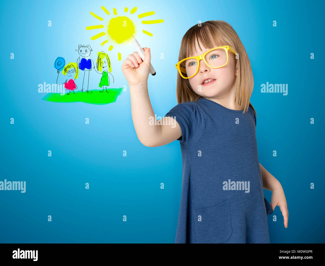 Cute little girl in yellow glasses draws herself and her family on glass. Stock Photo