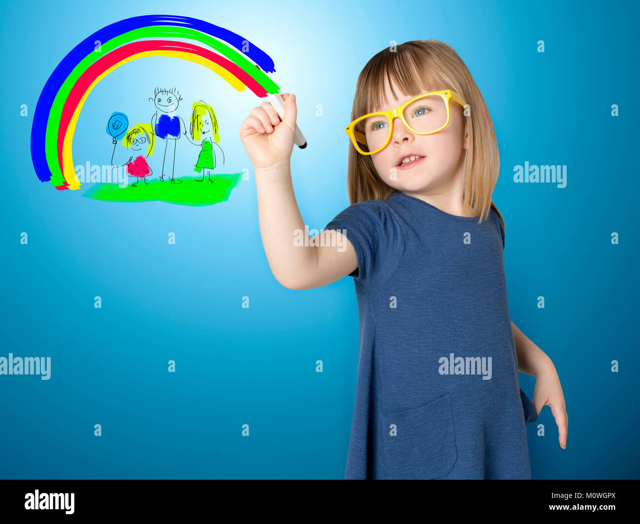 Cute little girl in yellow glasses draws herself and her family and a bright rainbow on glass. Stock Photo