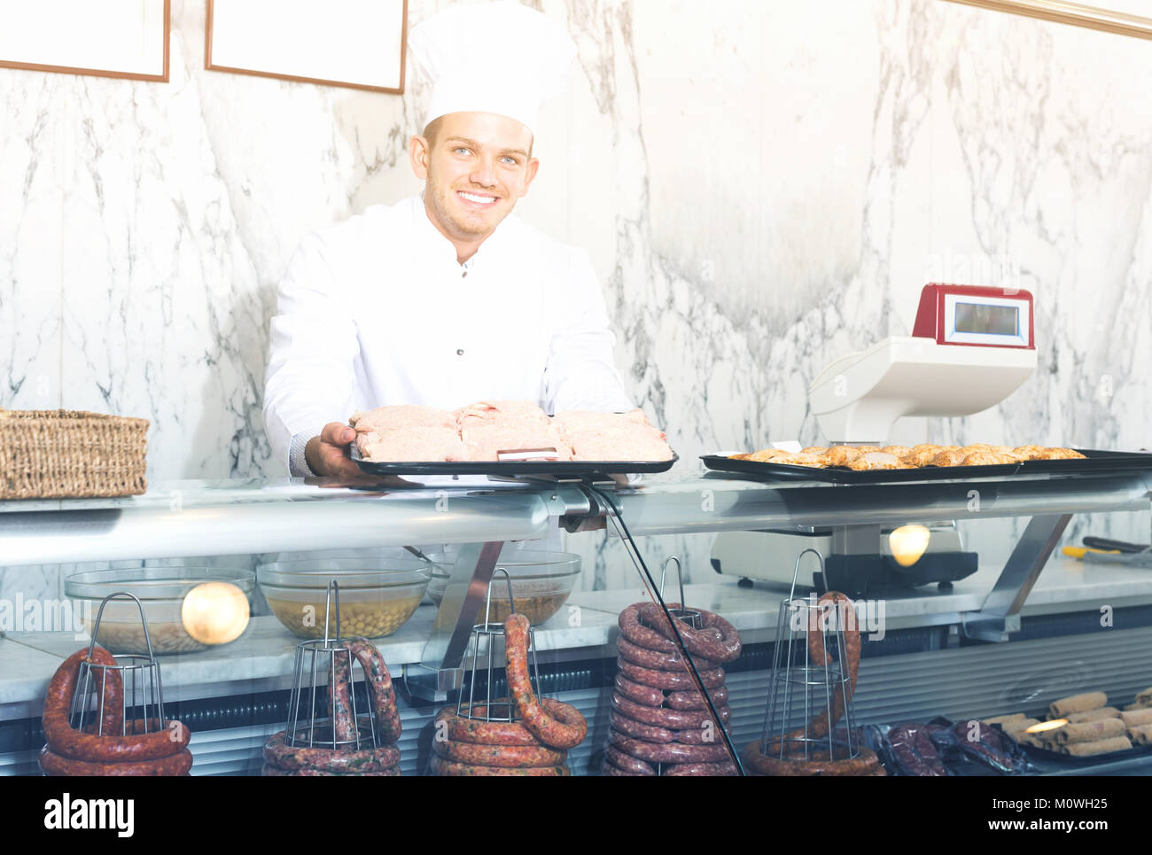 professional young seller at butcher store offering fresh products Stock Photo