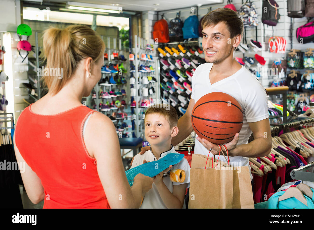 Cheerful young parents giving skateboard to their son in school age in ...