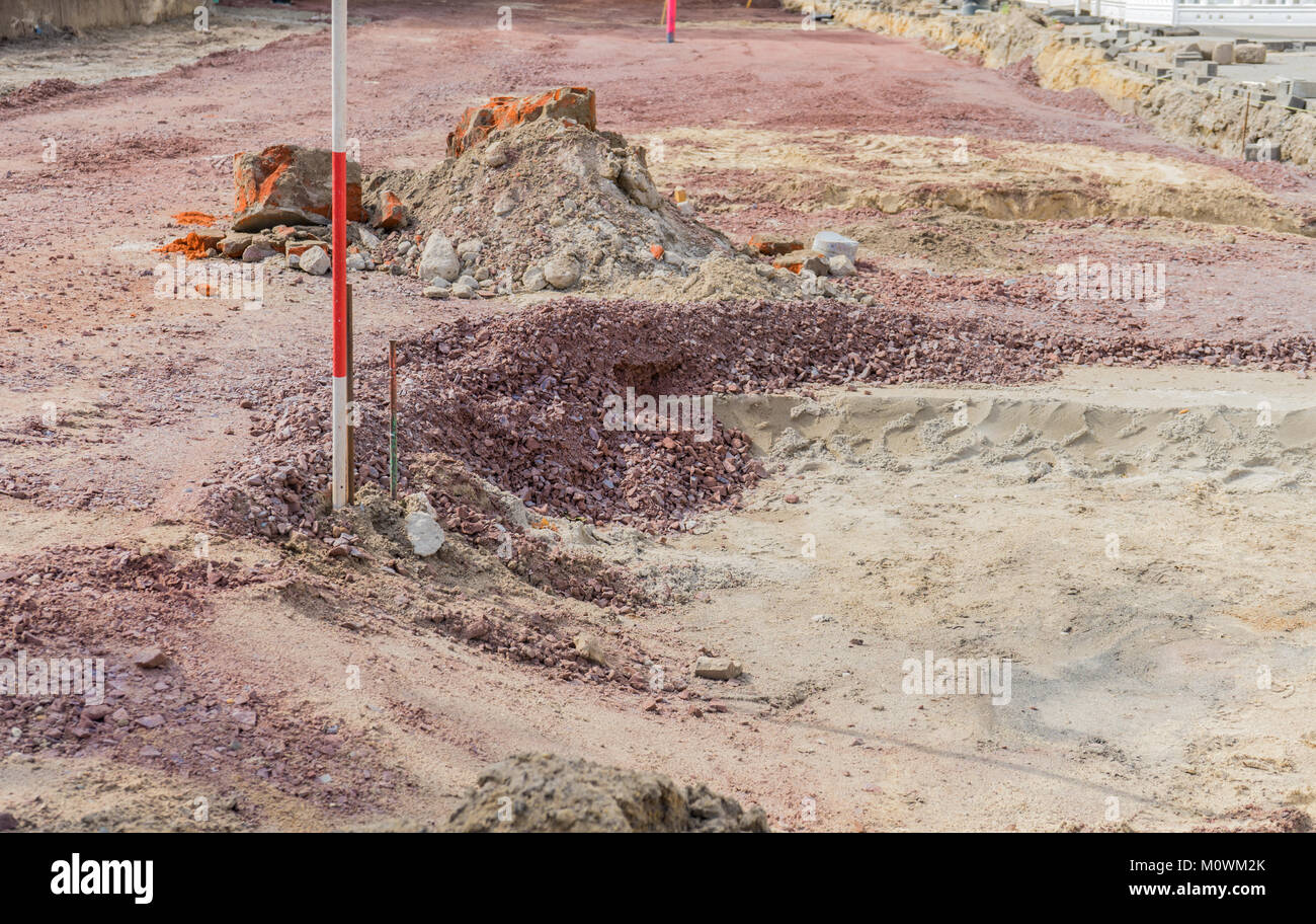 Excavation pit with sand and gravel and rod for height measurement Stock Photo